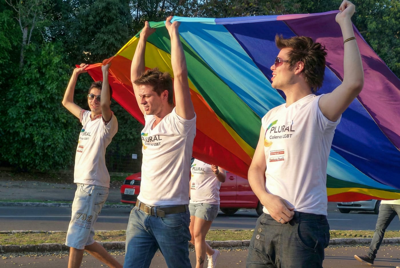 Integrantes do Plural, Coletivo LGBT, erguendo a bandeira do arco-íris durante a Parada da Diversidade em Passo Fundo